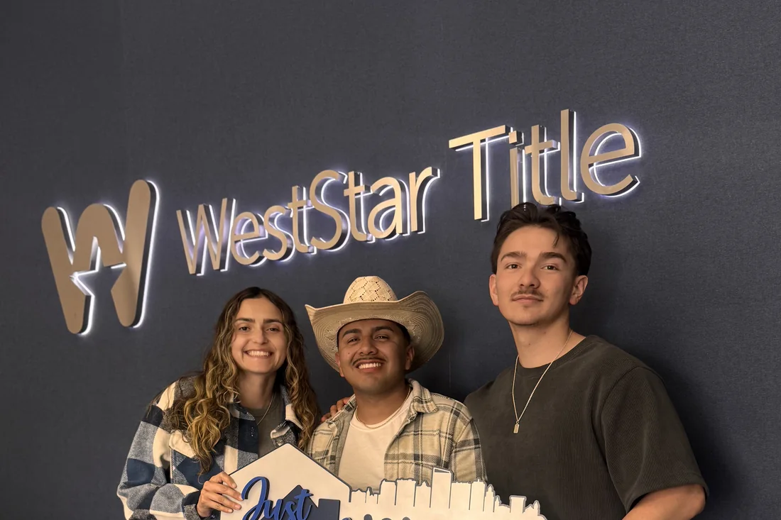 Isacc Lightbourn with clients holding a Just Closed key sign at WestStar Title