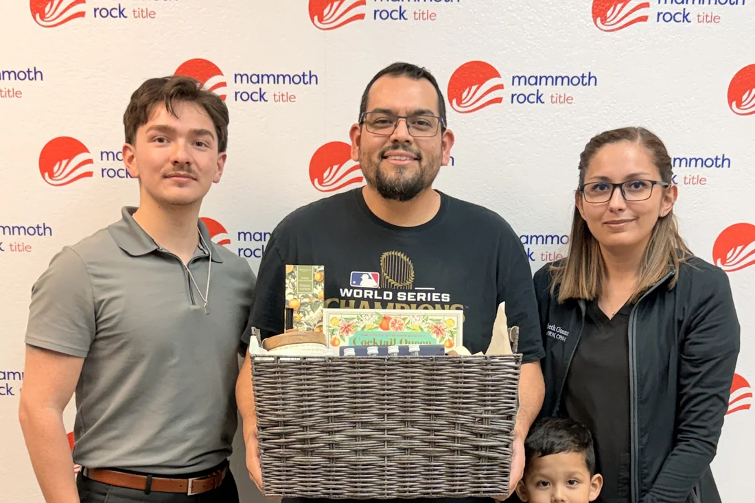 Isacc Lightbourn with a family holding a closing gift basket at Mammoth Rock Title